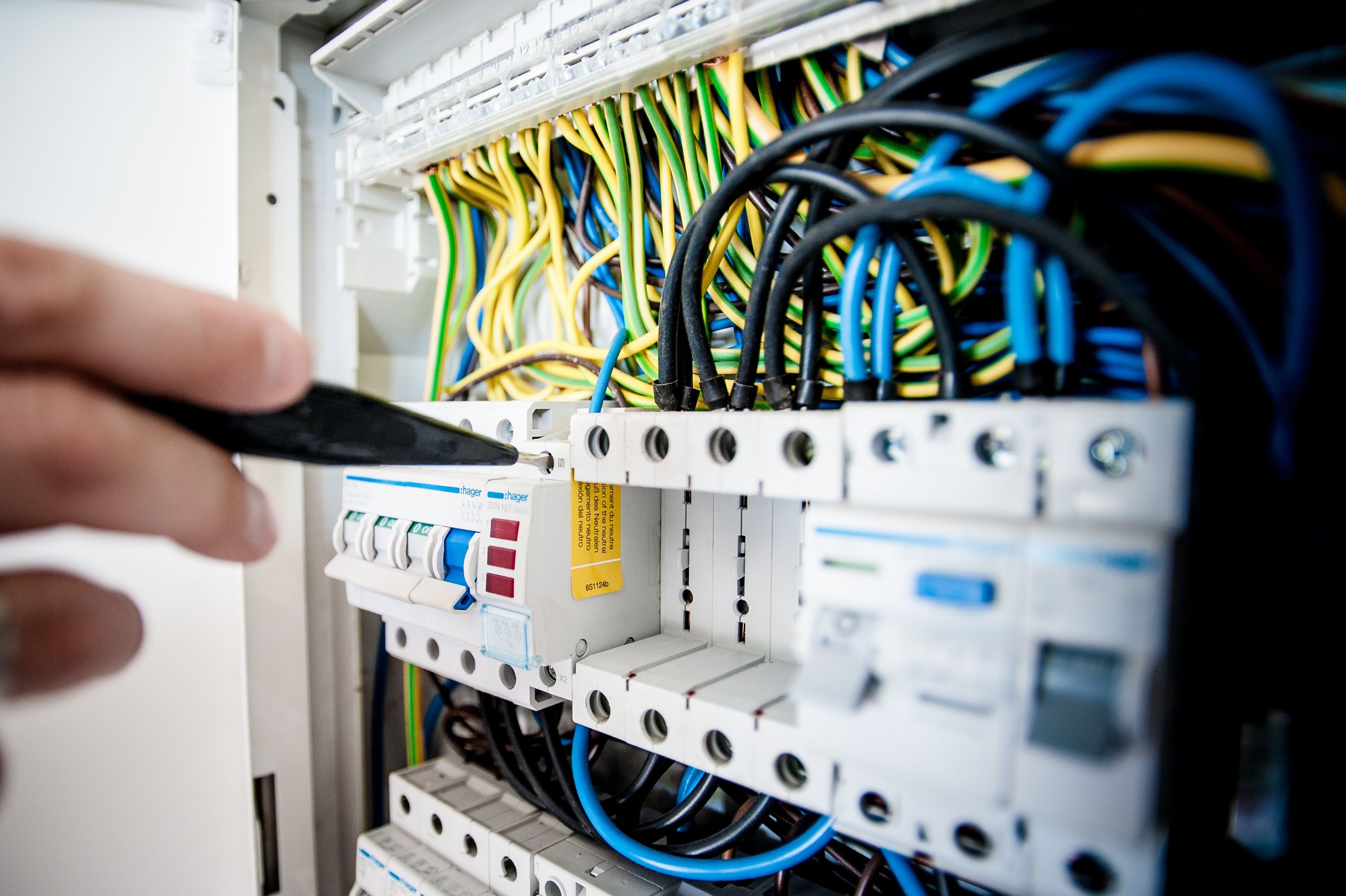 Electrician's hand working on a breaker panel with wires
